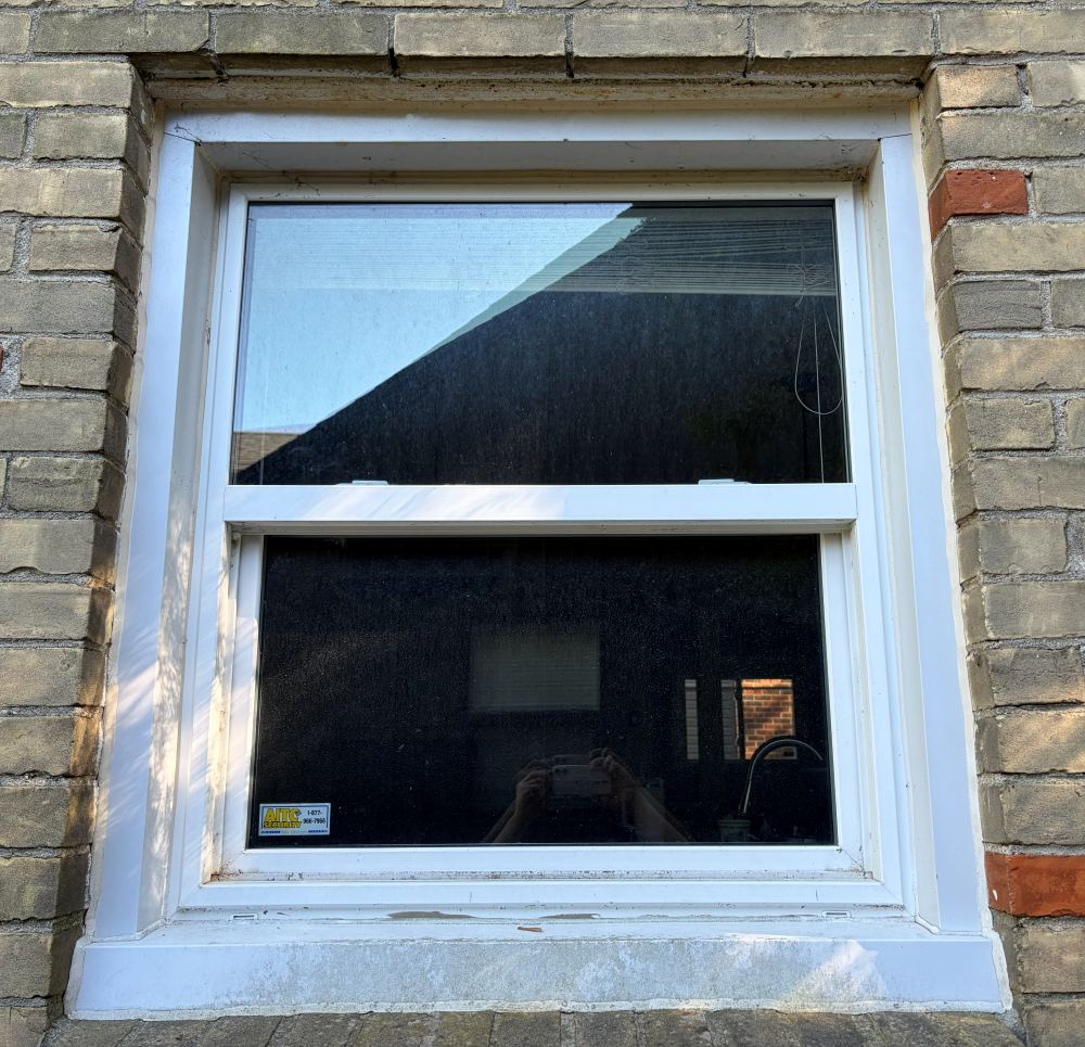 Kitchen window before cleaning, with dirt and spotting on the glass