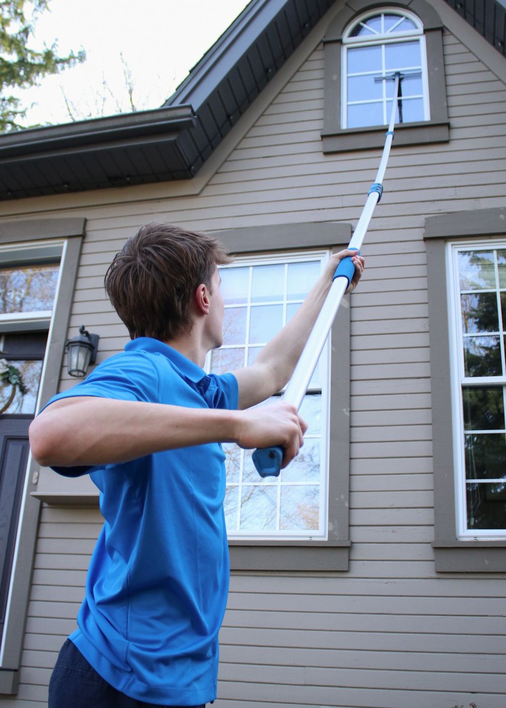 Cleaning a second-storey window from the ground using a telescoping pole, no ladders